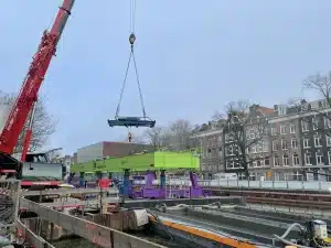 Een loopkat wordt op een portaalkraan gehesen met behulp van een mobiele kraan